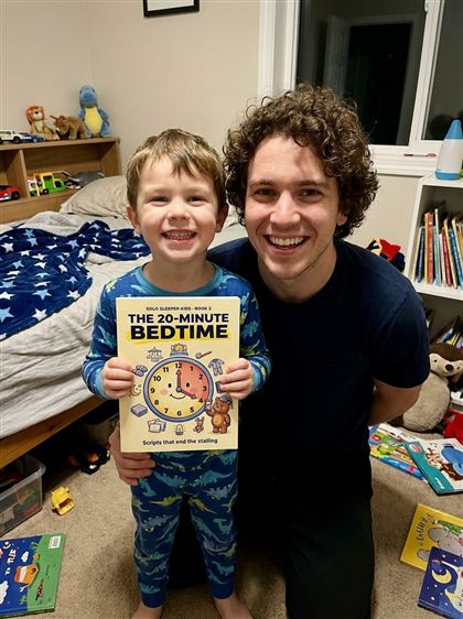 Dad and son in pajamas holding Book 2